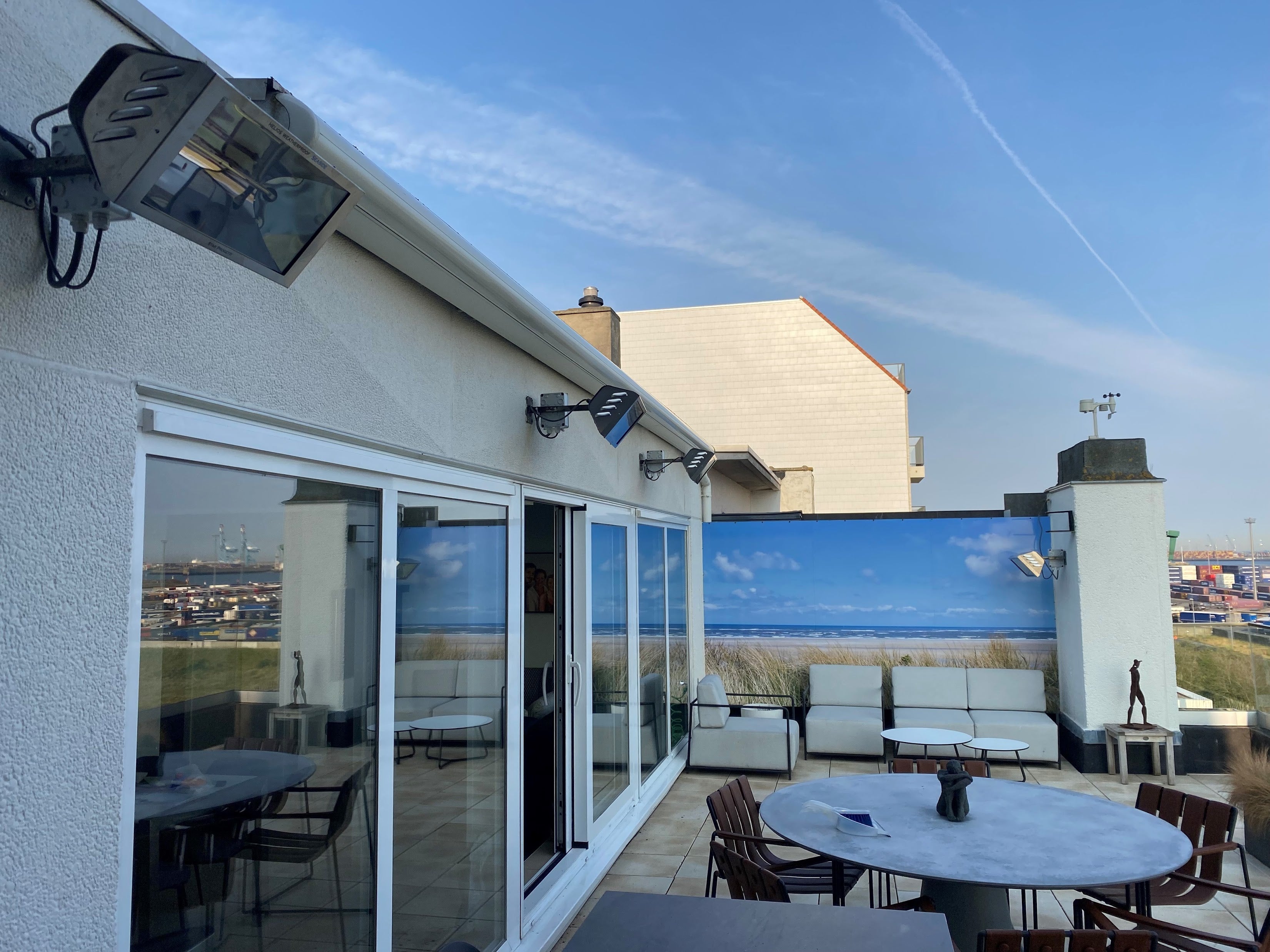 Terrasstralers tegen de muur gemonteerd boven een terras en een lounge aan de kust